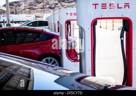 Eine große Sammlung von Tesla Superchargern in Aktion entlang der Interstate 15 in Baker, Kalifornien, USA. Das Netz der Kompressoren bildet das Rückgrat von Tesla“ Stockfoto