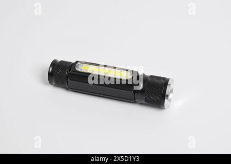 Moderne Metall-LED-Taschenlampe in schwarzer Farbe isoliert auf weißem Hintergrund. Tragbare Taschenlampe, LED-Campinglampe Stockfoto