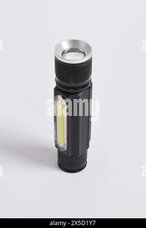 Moderne Metall-LED-Taschenlampe in schwarzer Farbe isoliert auf weißem Hintergrund. Tragbare Taschenlampe, LED-Campinglampe Stockfoto