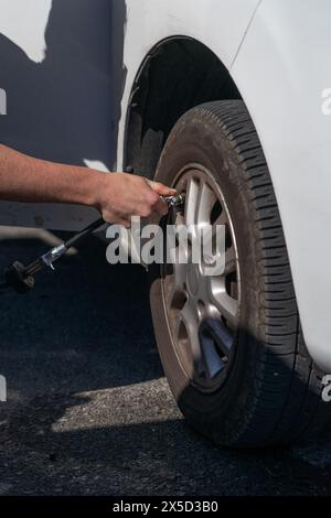 Die Hand eines Mannes, der einen Autoreifen aus der Nähe aufpumpt. Fahrzeugwartung Stockfoto