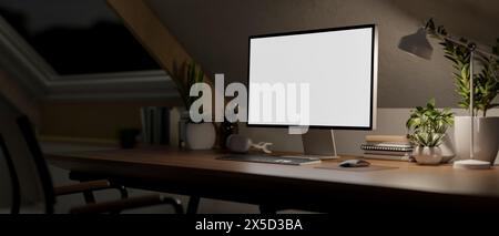 Ein moderner minimalistischer, dunkler Arbeitsplatz im Dachgeschoss bei Nacht mit dunklem Licht verfügt über einen Computer mit weißem Bildschirm und eine Einrichtung auf einem Stockfoto