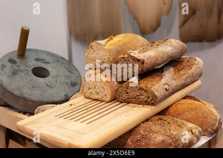 Mechanische Steinmühle im Retro-Stil und handwerkliches Bäckereibrot. Essen Stockfoto