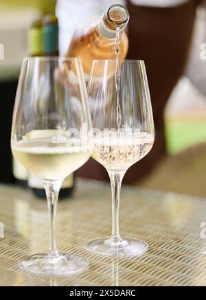 Person, Gläser und Flasche im Weingut für Weinprobe, Champagner und Alkoholgetränk mit Profi. Sommelier, Tisch und Getränk für Gastfreundschaft Stockfoto