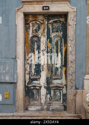 Abblätternde blaue, orange und weiße Farbe auf alten Doppelholztüren in der Rua Vasco da Gama Olhão 20, Algarve, Portugal Stockfoto