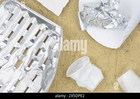 Sand nach dem Sommergrillen. Aluminium- und Kunststoffmüll. Stockfoto