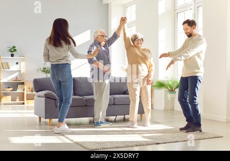 Ganze Familie alte Eltern Erwachsene Kinder lustig tanzen im Wohnzimmer lachen und lächeln. Familie lustig tanzen zu Hause alte Eltern Erwachsene Kinder Stockfoto