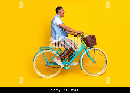 Foto in voller Länge von stauntem Mann gekleidete Jeans Weste Fahrradabsicht Leere Raum isoliert auf leuchtendem gelbem Hintergrund Stockfoto