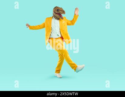 Energiegeladener junger Mann tanzt mit Dinosaurierkopfmaske Stockfoto