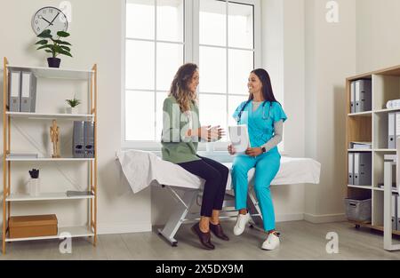 Positiver weiblicher Arzt, der sich mit dem Patienten im Krankenhauszimmer befasst Stockfoto