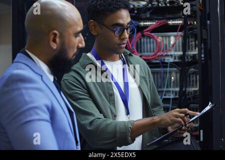 Mitarbeiter, Clipboard und Techniker im Serverraum, Mitarbeiter und Programmierer mit Papierkram. Männer, Kollegen und Unterstützung für Maschinen Stockfoto