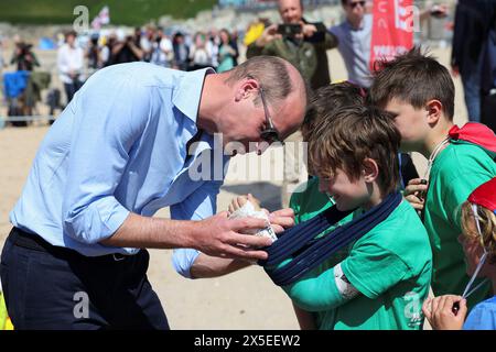 Der Prinz von Wales, bekannt als Duke of Cornwall in Cornwall, unterzeichnet die Besetzung von Felix Kanes, einem Mitglied des Holywell Bay Surf Life Saving Club, während eines Besuchs in Fistrall Beach in Newquay. Treffen mit lokalen Organisationen, die sich für die Sicherheit im Meer und am Strand einsetzen. Bilddatum: Donnerstag, 9. Mai 2024. Stockfoto