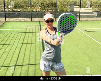 Ukraine Kiew, 03. Mai 2024. Porträt einer lächelnden Frau mit Padel-Tennisschlägerkopf auf dem Hof Stockfoto