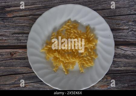 Close-up getrocknete Korkenzieher-Nudeln in einer weißen Schale auf einem Holztisch Stockfoto