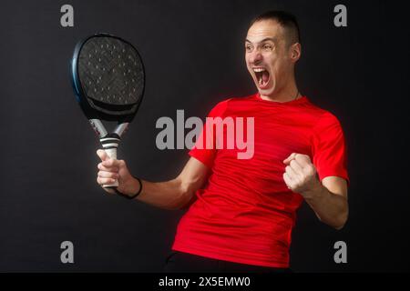 Lächelnder Mann mit Schläger und Paddelball in Sportkleidung gekleidet isolierter Hintergrund. Vorderansicht. Stockfoto