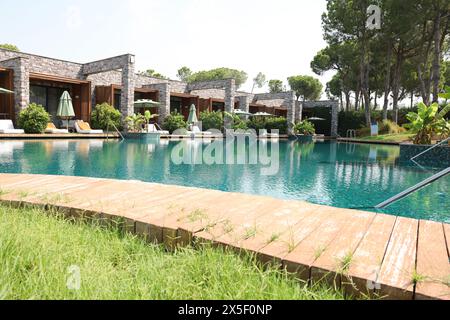 Außenpool mit Holzterrasse, Sonnenliegen und Sonnenschirmen im Resort Stockfoto