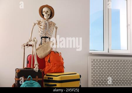 Wartendes Konzept. Menschliches Skelett im Hut mit Koffern drinnen Stockfoto