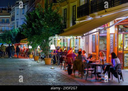 Abends können Sie in den beleuchteten Straßencafés im touristischen Viertel Barrio Santa Cruz der andalusischen Stadt Sevilla, Spanien, speisen. Stockfoto