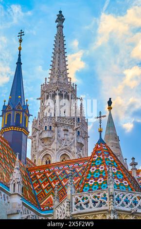 Der gotische Steinglockenturm, kleinere Türme und das verzierte Dach der Matthiaskirche, bedeckt mit Mustern der traditionellen Zsolnay-Fliesen, Budapest, Ungarn Stockfoto