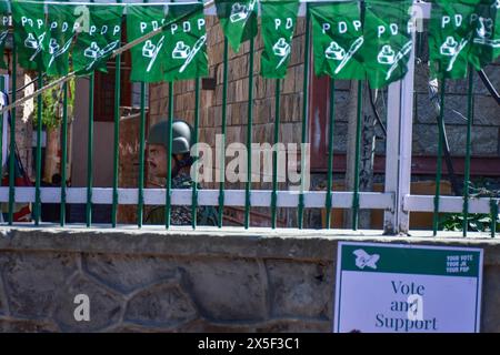 Srinagar, Indien. Mai 2024. Ein paramilitärischer Soldat hält Mahnwache, während Anhänger der Demokratischen Volkspartei (PDP) an einer Wahlkampagne im Vorfeld der vierten Wahlphase der indischen Parlamentswahlen in Srinagar teilnehmen. Quelle: SOPA Images Limited/Alamy Live News Stockfoto