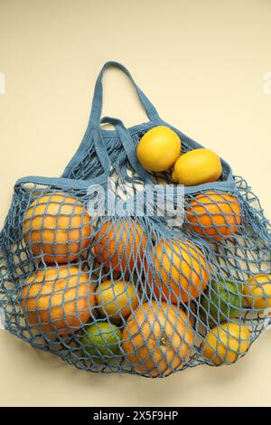 Schnur-Tasche mit verschiedenen Früchten auf beigem Hintergrund, Ansicht von oben Stockfoto