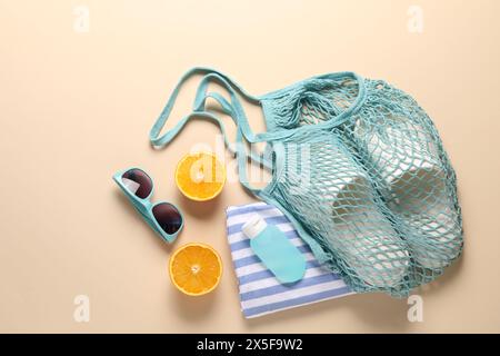 Schnur-Tasche, verschiedene Strandaccessoires und Orange auf beigefarbenem Hintergrund, flacher Lay Stockfoto