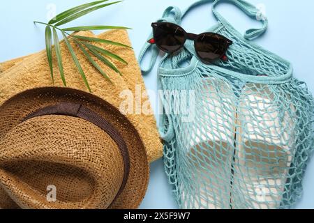 Schnur-Tasche, verschiedene Strandzubehör und Palmblatt auf hellblauem Hintergrund, flache Lay Stockfoto