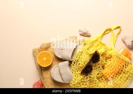 Schnur Tasche, verschiedene Strandzubehör und Orange auf beigefarbenem Hintergrund, Draufsicht. Leerzeichen für Text Stockfoto