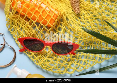 Schnur-Tasche, verschiedene Strandzubehör und Palmblatt auf hellblauem Hintergrund, flache Lay Stockfoto