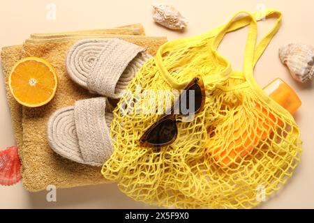 Schnur Tasche, verschiedene Strandzubehör und Orange auf beigefarbenem Hintergrund, Draufsicht Stockfoto