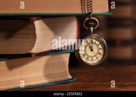 Taschenuhr hängt an einem Stapel Bücher an einem Holztisch, Großaufnahme Stockfoto