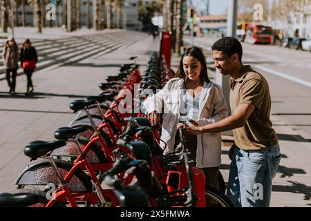 Junge Paare, die einen luftigen Tag mit Fahrrädern von einer Verleihstation in Barcelona verbringen. Stockfoto