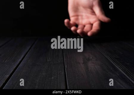 Mann, der Hand über schwarzem Holztisch hält, selektiver Fokus. Leerzeichen für Text Stockfoto