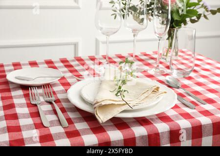 Stilvolle Einrichtung mit Besteck, Tellern, Serviette, Gläsern und Blumendekor auf dem Tisch Stockfoto