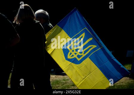 Warschau, Polen. Mai 2024. Am 9. Mai 2024 wird auf dem sowjetischen Militärfriedhof in Warschau, Polen, mit ukrainischer Flagge gesehen. Die Demonstranten unterbrachen den Besuch des russischen Botschafters Sergej Andrejew mit lauten Schreien, während sie Kleider trugen, die die Namen bombardierter ukrainischer Städte trugen und mit Bühnenblut bedeckt waren. (Foto: Jaap Arriens/SIPA USA) (Foto: Jaap Arriens/SIPA USA) Credit: SIPA USA/Alamy Live News Stockfoto