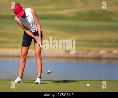 Eine junge Golferin, die einen Putt auf einem Golfplatz macht Stockfoto