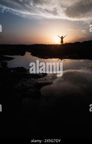 Frau am Meer bei Sonnenuntergang mit Armen Stockfoto