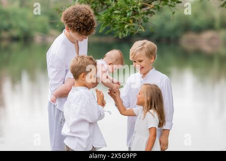 Kinder, Brüder und Schwestern spazieren im Sommer in der Nähe des Sees, eine große Familie. Hochwertige Fotos Stockfoto