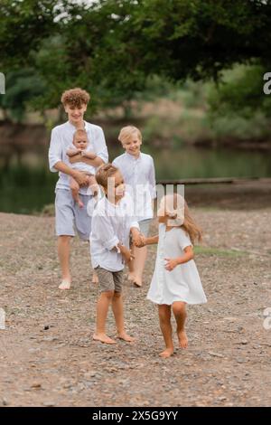 Kinder, Brüder und Schwestern spazieren im Sommer in der Nähe des Sees, eine große Familie. Hochwertige Fotos Stockfoto