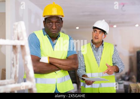 Porträt eines verwirrten Baumeisters, der mit einem Kollegen streitet Stockfoto