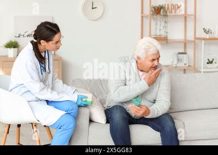 Seniorin mit Vernebler und Krankenschwester zu Hause Stockfoto