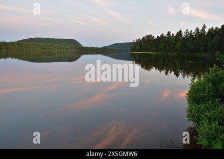 La Mauricie Nationalpark Wapizagonke See bei Sonnenuntergang. Ruhiges, blaues und rosafarbenes Wolkenreflexion auf stillem Wasser. Sandstrand im Hintergrund Stockfoto