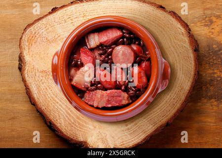 brasilianische Feijoada in Keramikschale isoliert auf rustikalem hölzernem Hintergrund. Kopierbereich. Draufsicht Stockfoto