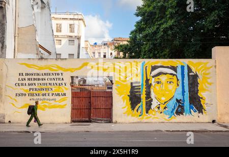 Soldat passiert Havanna Wandgemälde. Der Text lautet: "Die Schikanen und Maßnahmen gegen Kuba sind unmenschlich und bestehen fort, das muss aufhören. Keine Blockade mehr Stockfoto