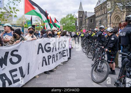 Jüdische Studenten, die Palästinenser unterstützen, halten während der Kundgebung ein Banner mit der Aufschrift "Juden gegen die israelische Apartheid" vor der menschlichen Barrikade der Polizei. Pro-palästinensische und pro-israelische Demonstranten an der University of Toronto außerhalb des Studentenlager im King College Circle. Studenten und Dozenten, die sich für die palästinensischen Rechte einsetzten, zeigten Banner, die die Not der Palästinenser darstellten, antizionistische und anti-israelische Botschaften, während pro-israelische Proteste Studenten und Unterstützer daran beteiligten, israelische Flaggen zu schwenken und Dialoge zu führen, um Israels Aktionen und Politik zu verteidigen. Stockfoto