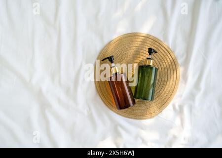 Zwei Pumpflaschen, eine braune und eine grüne, enthalten Seife, Lotion oder ein anderes flüssiges Produkt für die Körperpflege oder Reinigung auf einem kreisförmigen Gewebe Stockfoto