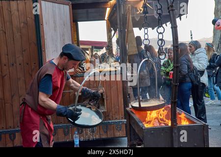 Baiona, Pontevedra, Galicien, Spanien; März 2023; ein mittelalterlicher Koch macht Pfannkuchen mit Feuer vor dem aufmerksamen Blick der Menschen Stockfoto