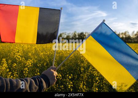 Flaggen der Ukraine und Deutschlands gegen blühendes Rapsfeld und blauen Himmel. Konzept der Zusammenarbeit und Partnerschaft zwischen zwei europäischen Ländern. S Stockfoto