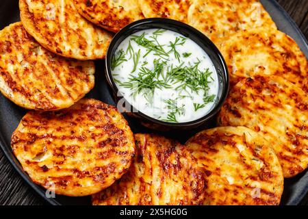 Gebacken im Ofen mit hohem Eiweißgehalt herzhafter Hüttenkäse Parmesan und Dill-Pfannkuchen auf Teller mit Sauerrahm, holländische Winkelansicht, Nahaufnahme Stockfoto