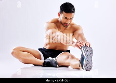Asiatischer Mann, Studio und Stretchbeine für Trainingsübungen im Boden oder auf weißem Hintergrund. Flexibel aufwärmen, Fitness- oder Sportsportler Stockfoto