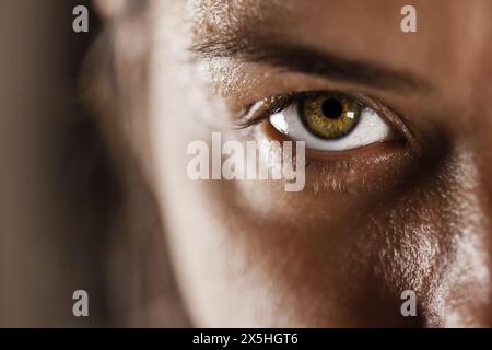 Dieses Bild zeigt eine Nahaufnahme des Auges einer Frau mit detaillierter Textur, natürlicher Haut und einer lebendigen Iris, die einen starken und fokussierten Blick reflektiert. Stockfoto